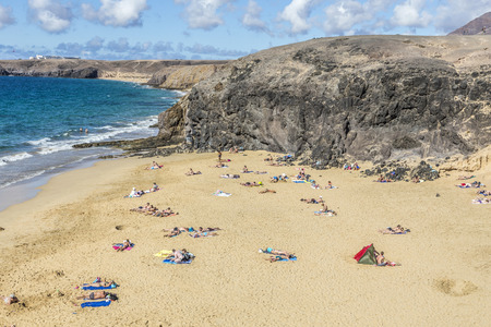PLAYA BLANCA, SPAIN - NOV 18, 2014: Many tourists enjoy Papagayo beach on a sunny  day in Playa Blanca, Spain. The beaches belong to a protected nature area.のeditorial素材