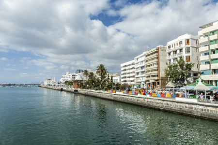 ARRECIFE, SPAIN - NOV 17, 2014: people walk along the promenade in Arrecife, Spain. The modern promenade was restored in 2008 and enables a relaxed walk for people along the scenic ocean and the harbor.のeditorial素材