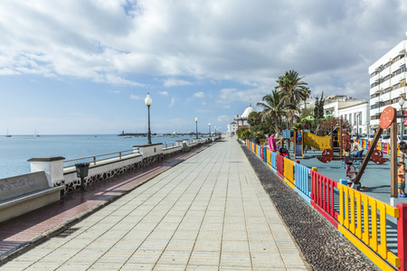 ARRECIFE, SPAIN - NOV 17, 2014: people walk along the promenade in Arrecife, Spain. The modern promenade was restored in 2008 and enables a relaxed walk for people along the scenic ocean and the harbor.のeditorial素材