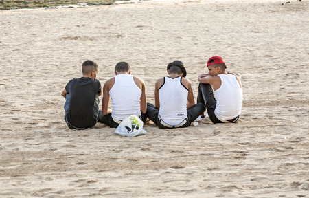 ARRECIFE, SPAIN - JAN 1, 2010: young people wearing Bro tanks sit at the beach and discuss in Arrecife, Spain. Youth culture is also defined by different clothing like Bro tanks.のeditorial素材
