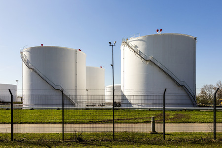 white tanks in tank farm with iron staircase under blue skyのeditorial素材