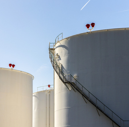 white tanks in tank farm with iron staircase under blue skyのeditorial素材