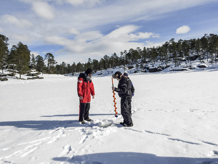 INARI, FINLAND - APR 2, 2015: tourists do ice fishing in Inari, Finland. The lake Inarijarvi and tours for 5 hour ice fishing are offered to tourists.のeditorial素材