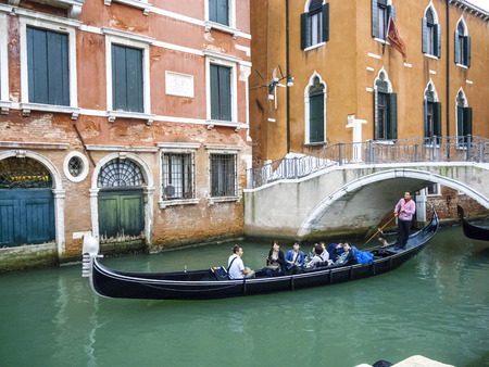 VENICE, ITALY - SEP 12, 2014: Venetian gondolas with tourist sail in the canal in Venice. Permissions for gondolas are very expensive and limited.のeditorial素材