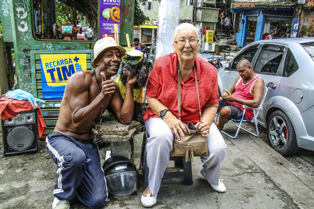 RIO DE JANEIRO - BRAZIL, JAN 31, 2015: european senior woman has a rest at a local food stand and poses with the owner and his dog in Rio de Janeiro, Brazil.のeditorial素材