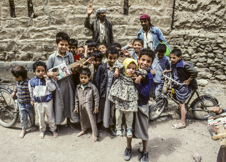 SHIBAM, YEMEN - JAN 1, 1991: family with other children pose for photo in Shibam, Yemen. They carry hand made toys with them like selfmade guitar.のeditorial素材
