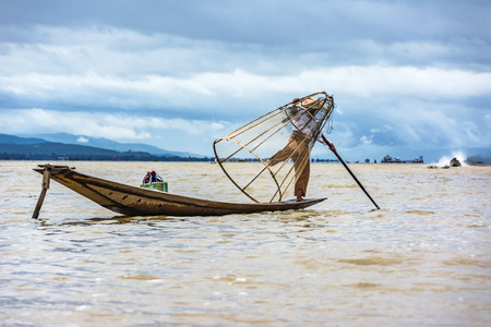 Heho, Myanmar - AUG 15, 2015 : Intha fisherman fishing  in his typical canoe with fishing net. The fishing net is handmade by the fisher.のeditorial素材