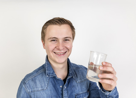 portrait of cute teenage boy drinking water isolated on whiteの写真素材