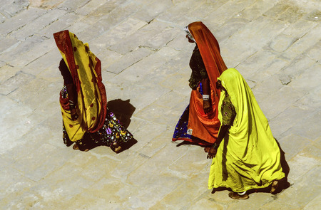 JAISALMER, INDIA - MAY 25, 1989: women in traditional clothes walk barefoot in the temple area in jaisalmer, India. Only 47 percent of the indian population is female with indication to decrease.のeditorial素材