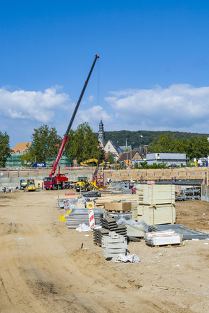 HOFHEIM, GERMANY - SEP 22, 2009: workers assist the crane carrying building material to the construction site. Safety regulations at construction sites are very strict in Germany and controlled by officials.のeditorial素材