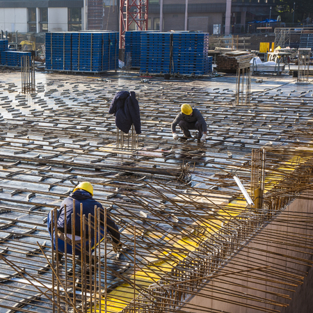 HOFHEIM, GERMANY - OCT 19, 2009: workers assist the crane carrying building material to the...