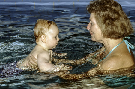 grandma and baby enjoy baby swimming in the poolの写真素材