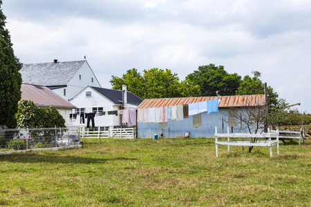 FARMSTEAD, USA - JULY 13, 2010: typical amish farm house with amish clothes at a clothes line and a man repairing a hutのeditorial素材