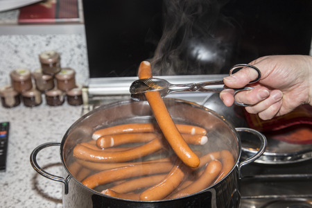 sausages are boiling in a pot of waterの写真素材