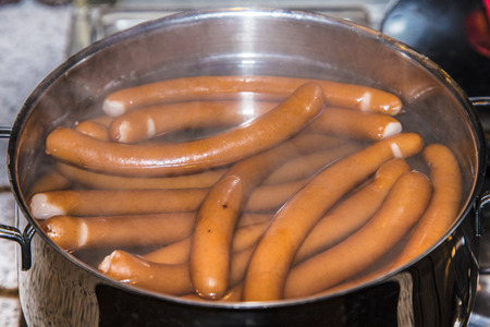 sausages are boiling in a pot of waterの写真素材