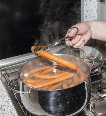 sausages are boiling in a pot of waterの写真素材