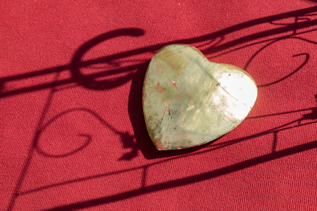 big golden heart on a red carpet with shadowの写真素材