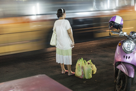 BANGKOK, THAILAND - MAY 6, 2009: woman waits at the Sukhumvit road in Bangkok for a taxi after shopping.のeditorial素材