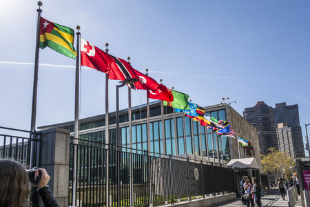 NEW YORK, USA - OCT 5, 2017:   UN Nations building with flags of participating countries in sun.のeditorial素材