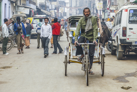 NEW DELHI, INDIA - DEC 10, 2010: indian rickshaw driver looks for passengers in the old part of New Delhi. The rickshaws are registered by New Delhi Police.のeditorial素材