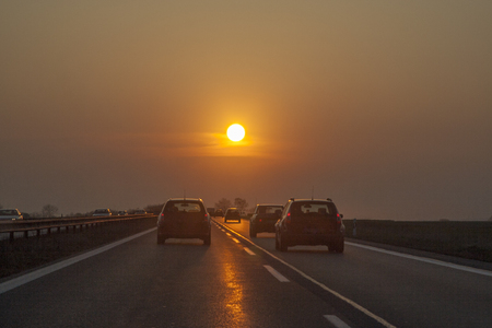 traffic at the european highway with cars and romantic sunset in frontの写真素材