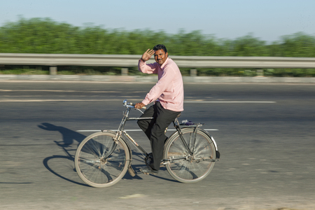 JEWAR BANGER, INDIA - NOV 12, 2011: tman rides bicycle at the Yamuna express highway in Jewar Banger, India. The Highway is a toll road and was finally inaugurated at August 2012.のeditorial素材