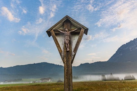 wooden crucifix in the tyrolean alps in morning time on a meadowの写真素材