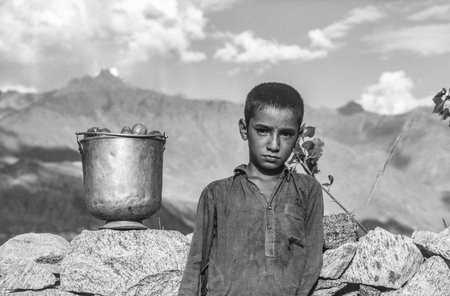 GILGIT, PAKISTAN - JUNE 30, 1986: local farmer boy takes home the picked ripe tomatos. Children have to help in the smaller farms.のeditorial素材