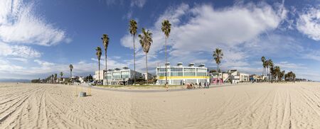 VENICE, USA - MAR 5, 2019: people enjoy scenic beach promenade with palms and colorful houses at Venice Beach in California.のeditorial素材
