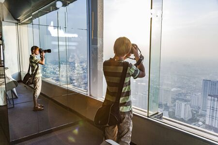 Bangkok, Thailand - January 2, 2010: people enjoying looking at   Bangkok skyline from the platform at the  viewpoint Mahanakhon Skywalk.のeditorial素材
