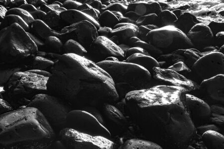 pebble stone beach in morning light with harmonic reflectionsの写真素材