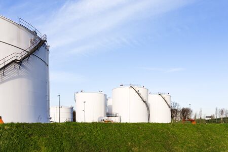 white tanks for petrol and oil in tank farm with blue sky