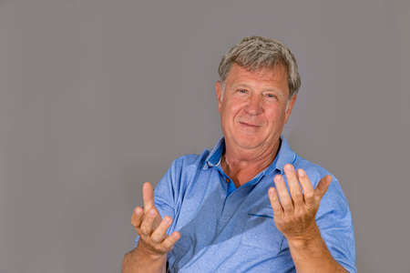 portrait of sixty year old attractive senior man in blue shirt isolated on grey