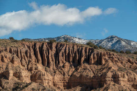 Landscape of grassy plain, sagebrush, and colorful cliffs under a vast blue sky in the high desert...