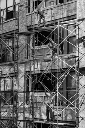 New York, USA - October 21, 2015: workers at a construction site are working on a scaffold at an old typical new york brick building.のeditorial素材
