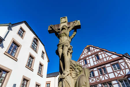 Bernkastel-Kues, Germany - February 21,2021: Half-timbered houses in Bernkastel-Kues, Germany with jesus statue under blue sky.のeditorial素材
