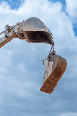 heavy excavator bucket under cloudy and blue sky in detailの写真素材