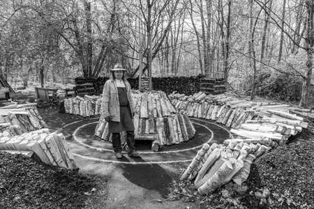 Neu Anspach, Germany - April 15, 2021: the charcoal burner prepares the wood at Hessenpark in Neu Anspach. Since 1974, the traditional jobs are shown at the museum to the audience.のeditorial素材