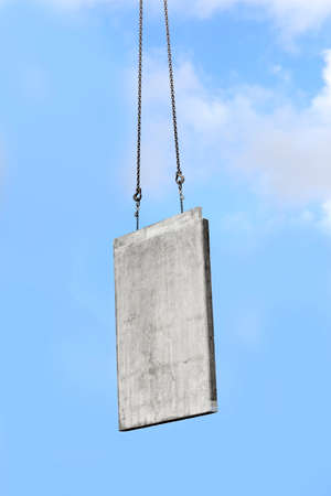 concrete wall at the construction site on the hook of a crane under blue sky