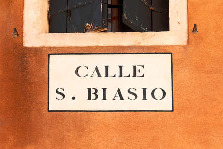 signage calle San Biasio - engl: street of holy Biasio - in Venice at an old grunge house wallの写真素材