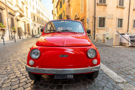 Rome, Italy - July 31, 2021: vintage red Fiat 500 parked next to a restaurant in Rome in the inner...