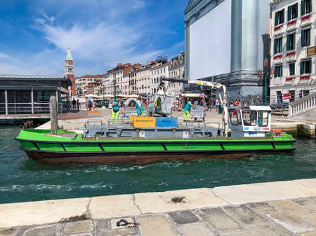 Venice, Italy - July 5, 2021: garbage men collect the garbage from the houses and transport it to a garbage ship.のeditorial素材