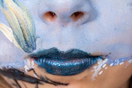 detail of mouth in blue painted colorful faceの写真素材