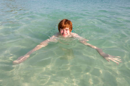 boy enjoys swimming in the beautiful sea with crystal clear water and blue sky, Thailandの写真素材