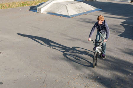 Eschborn, Germany - October 12, 2009: young red haired boy is jumping with his BMX Bike at the skate park with fun.のeditorial素材