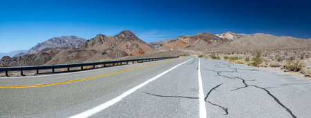 empty straight road through the death valley with yellow median, USA