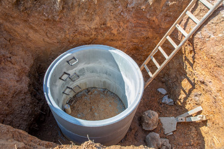 hole with concrete cistern at construction site and ladder for worker