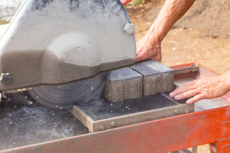 man with a cutting machine cuts a concrete curb