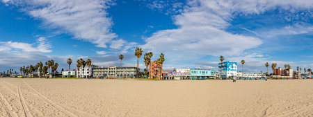 Venice, USA - March 5, 2019: people enjoy scenic beach promenade with palms and colorful houses at Venice Beach in California.のeditorial素材