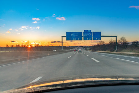 Frankfurt, Germany - February 10, 2021: german highway in sunset with driving cars and sun reflectionのeditorial素材